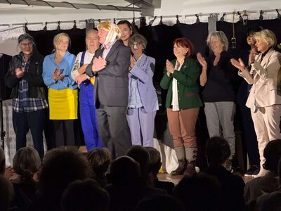 Eine Gruppe von Schauspielern steht auf der Bühne und nimmt den Applaus des Publikums im Theater entgegen.